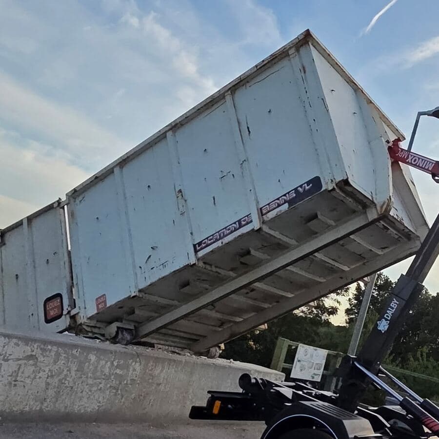 Benne blanche basculée par le bras du camion au-dessus du quai tout-venant d’une déchèterie